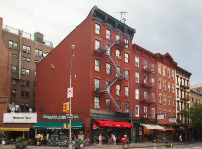 Red brick building in Greenwich Village, New York City with pizza shop and other retail on ground floor.