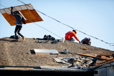 construction workers on the roof of a house.