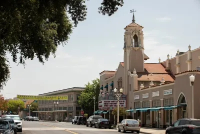 Street in Hanford, California with old Spanish-style church with tall steeple and cinema-style marquee.
