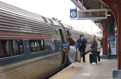 Passengers boarding an Amtrak train at an outdoor platform in Wilmington, Delaware.