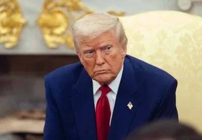 Trump in a navy suit frowns at the camera.