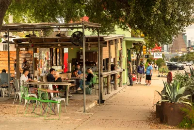 Wooden shops and restaurants in Austin, with people mingling.