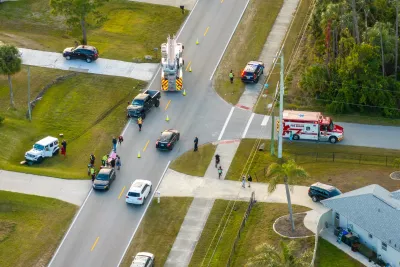 Aerial of traffic crash at intersection with ambulance and first responders on scene.