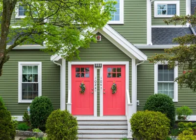 Green traditional duplex with red doors.
