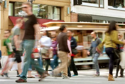 Blurred pedestrians crossing busy crosswalk in San Francisco, California.