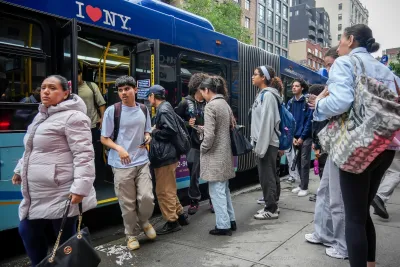 People boarding and deboarding blue NYC bus.