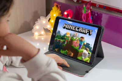 Close-up over shoulder of child looking at Minecraft video game splash page on iPad.