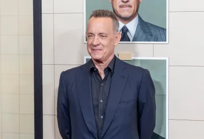 Tom hanks stands in front of film posters at premiere of The Phoenician Scheme in New York CIty.