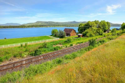 Railroad tracks in Idaho passing a home by a river.