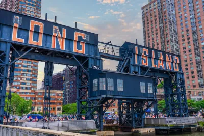 Red 'Long Island' text on blue steel bridge/gates over river.