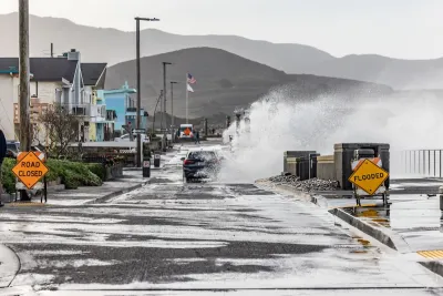 A car drives through a puddle, making a large splash. Rain pours down.