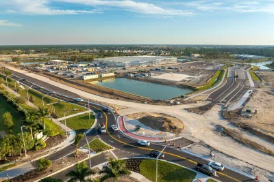 Roundabout under construction with cars moving around one side of it.