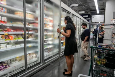 People looking into the frozen foods aisle at a grocery store.