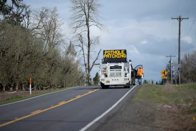 Road repair crew with sign reading 'Pothole Repair' on road.