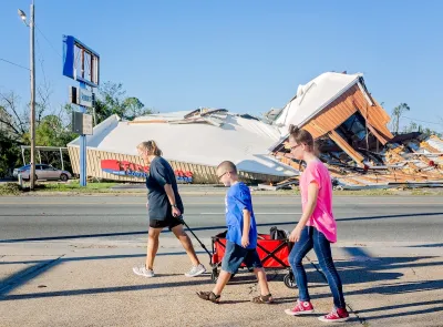 A Florida family with their belongings in a wagon walks past a destroyed storm after a hurricane. 