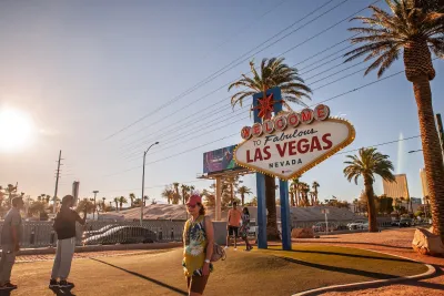 People standing in front of famous Las Vegas sign in warm-toned photo.