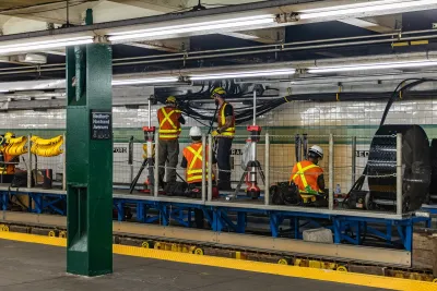 Workers inorange vests working on station infrastructure in New York City subway station.