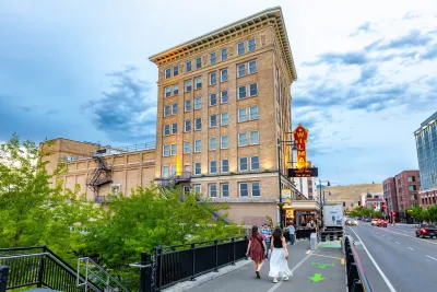 People walking on walkway and bike path next to historic brick building in downtown Missoula, Montana.