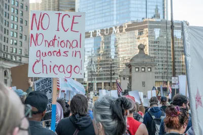 Crowd of protesters with white sign with red lettering reading "No ICE No National Guard in Chicago."