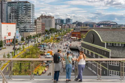 View from behind group of people on bridge looking down onto crowd in front of Seattle Aquarium.