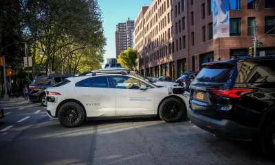 White Waymo SUV in traffic on New York City street.