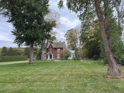 Two-story brick house on large lot with green lawn and mature trees in Connecticut.