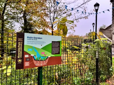 A sign on a fence describing the rain garden behind it.