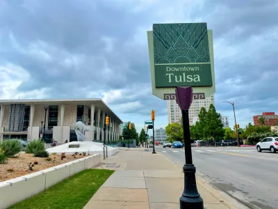 Downtown Tulsa sign and street view with the Tulsa Performing Arts Center under stormy skies.