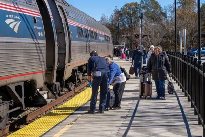 People with luggage on train platform next to silver Amtrak train in Selma, North Carolina.