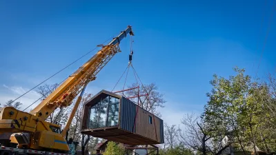 Modular home being dropped onto site with large crane.