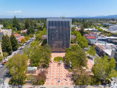 High-rise simple modernist Palo Alto,California City Hall building with open plaza lined by trees in front.