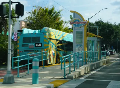 Green Sunrunner bus at elevated mid-street bus stop with dedicated bus lane in St. Petersburg, Florida.