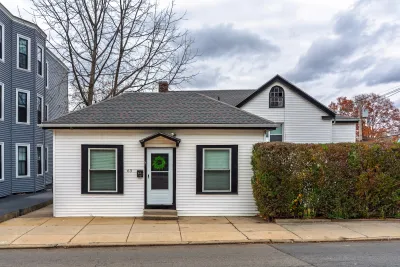 Small white clapboard home in Boston, Massachusetts with green wreath on black front door.
