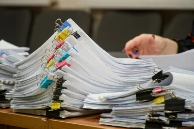 Close-up on stacks of papers clipped together with multicolored alligator clips on a desk.