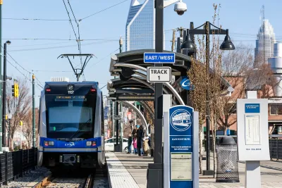 A sleek light rail glides through Charlotte, NC, carrying commuters and visitors past busy neighborhoods, skyline views.