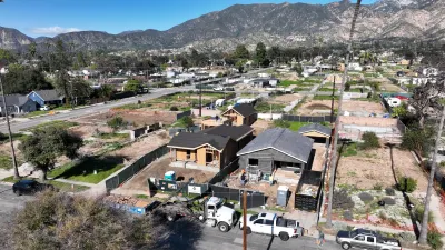 Aerial of two homes under reconstruction in fire-damaged area of Altadena, California with mountains in background.