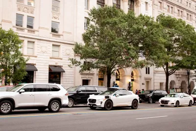 White Waymo cars lined up next to a white neoclassical building in Washington D.C.