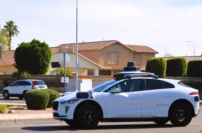 White Waymo robotaxi in fron tof Southwestern Spanish revival house in Phoenix, Arizona.