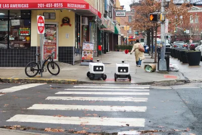 Two small white robots at crosswalk in Hoboken, New Jersey.