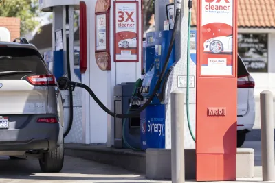 Silver car parked at gas station with gas pump fueling it with no owner there.
