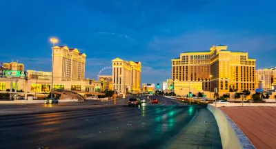 Blurred cars speeding on highway with Las Vegas strip skyline in background.