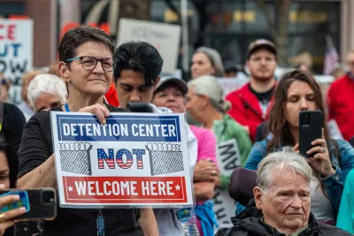 Woman in crowd holding sign saying "Detention center NOT welcome here" at protest against ICE detention center in Monroe, Georgia.