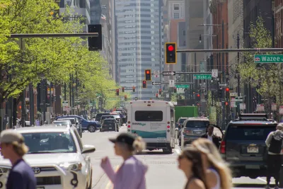 Pedestrians crossing a crosswalk with city traffic and bus in ackground in Denver, Colorado.