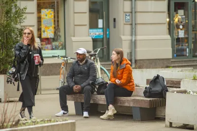 Man and woman sitting on public bench on busy street in Riga, Latvia.