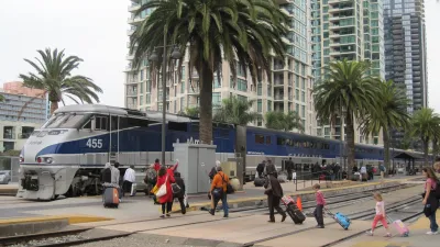 Silver and blue Amtrak Surfliner train at platform in San Diego, California with passengers walking next to it.