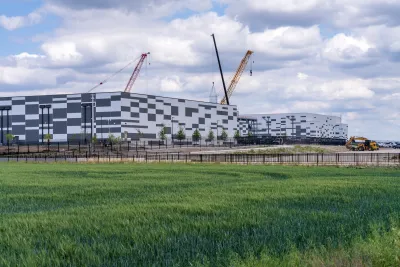 Exterior shot of the Skybox Power Campus data center building in Hutto, Texas with cranes visible on a partly cloudy day.