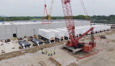 Data center complex under construction in field surrounded by green forest in Texas.