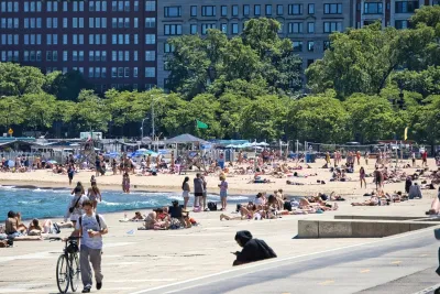 People sunbathing and hanging out on concrete seawall and sandy beach on Lake Superior in Chicago, Illinois.