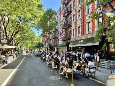 People drinking at outdoor tables in front of Bua bar on the Open Street, a car-free pedestrian zone, on St. Mark's Place in the East Village, Manhattan, New York City