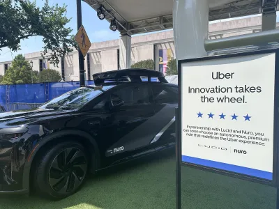 Black Uber self-driving car on display with sign.
